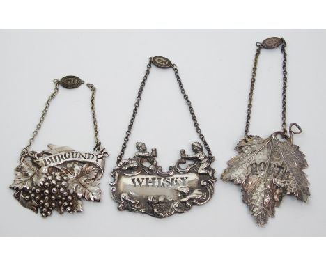 A silver decanter label by Hugh Johnson, Birmingham 1993, the scrolling edges embossed with drinkers in various poses and pie