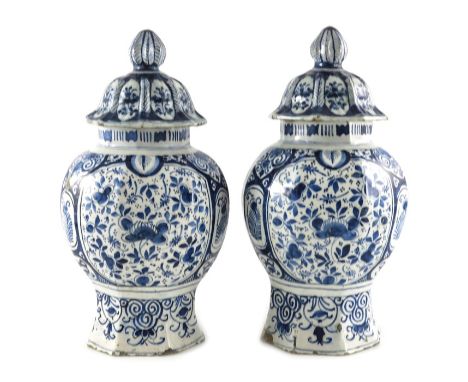 A Pair of English Delftware blue and white vases with covers, circa 1700, of baluster form and decorated in panels with leaf 