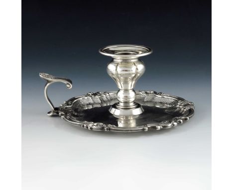 An early Victorian silver chamber stick, WE, London 1838, the pear baluster sconce within a cast shell and scroll border with