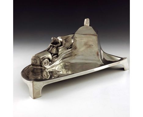 Orivit, a Jugendstil pewter inkwell, circa 1915, relief moulded with a car and driver speeding down a hill, the well lid with