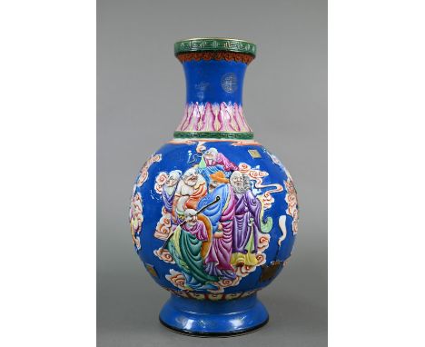 A Chinese famille rose blue ground vase decorated in high-relief with a dragon flying over various Daoist immortals upon clou
