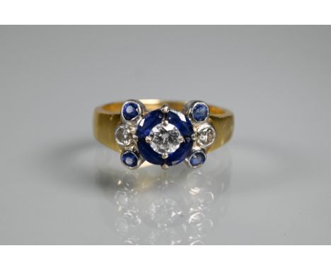 An sapphire and diamond cluster ring, the central round brilliant cut diamond surrounded by four marquise cut deep blue sapph