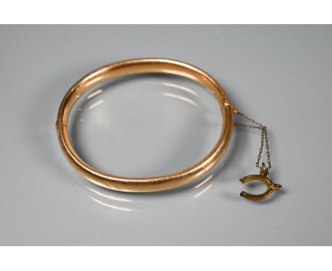 A yellow metal half hinged oval bangle with concealed clasp and safety chain, stamped 15ct, approx 12.4g&nbsp; Bruised overal