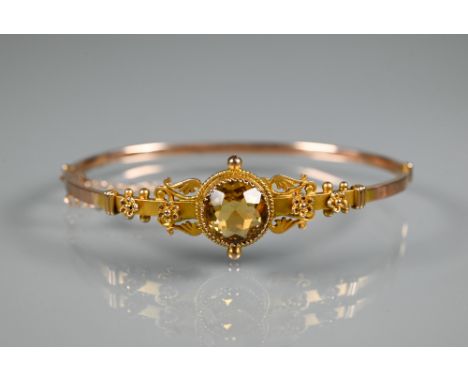 A Victorian 9ct yellow gold half hinged bangle with flower and scroll decoration and central circular citrine, stamped 9c, ap