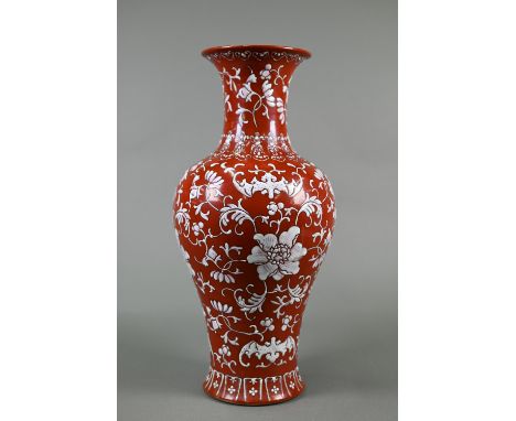 A Chinese coral ground baluster vase painted in white enamels with four bats and composite floral scroll with ruyi-heads arou