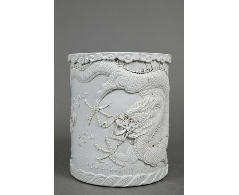 A Chinese monochrome cylindrical brush pot, bitong, the exterior decorated in high relief with a fierce dragon in pursuit of 