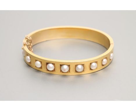 A LATE VICTORIAN STIFF HINGED BANGLE, the upper section set with nine split pearls in square panels, unmarked (Est. plus 21% 