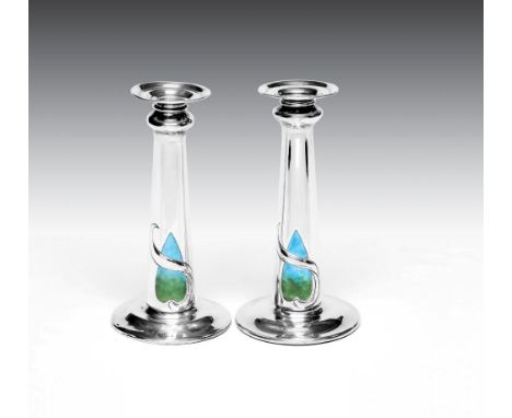 A PAIR OF EDWARDIAN ARTS AND CRAFTS SILVER AND ENAMEL CANDLESTICKS, maker William Hutton &amp; Sons Ltd., London 1903, the de