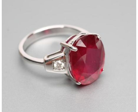 A RUBY RING, the oval facet cut stone claw set to shoulders each set with a small round brilliant cut diamond in a square set