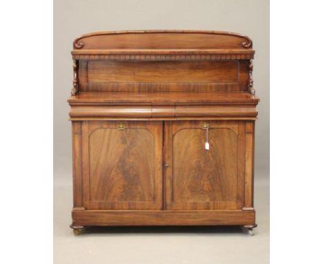 AN EARLY VICTORIAN MAHOGANY CHIFFONIER, the mildly arched panelled back with shelf on leaf and scroll carved supports, the cu