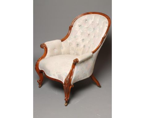 A VICTORIAN WALNUT FRAMED SALON ARMCHAIR of spoon back form, button upholstered in an ivory floral weave, moulded frame, scro