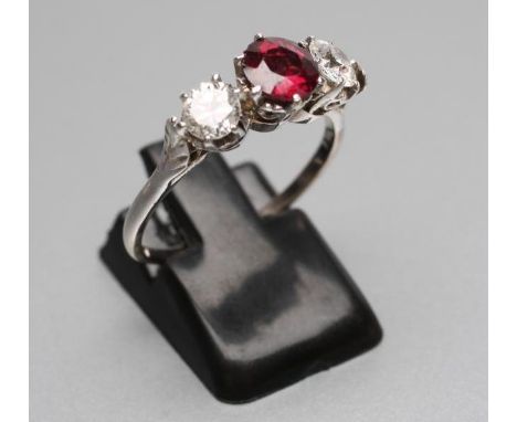 A RUBY AND DIAMOND THREE STONE RING, the central facet cut ruby claw set and flanked by two brilliant cut diamonds each of ap