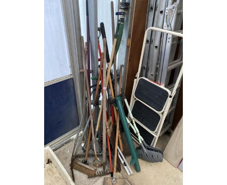 A LARGE ASSORTMENT OF GARDEN TOOLS TO INCLUDE RAKES, BRUSHES AND SPADES ETC 