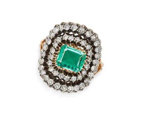 AN EMERALD AND DIAMOND CLUSTER RING in yellow gold and silver, set with an octagonal step cut emerald of approximately 0.80 c