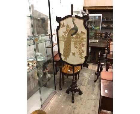 A 1920s/30s pole screen with a stumpwork panel depicting a peacock and other birds, on pedestal support (180cm x 64cm)