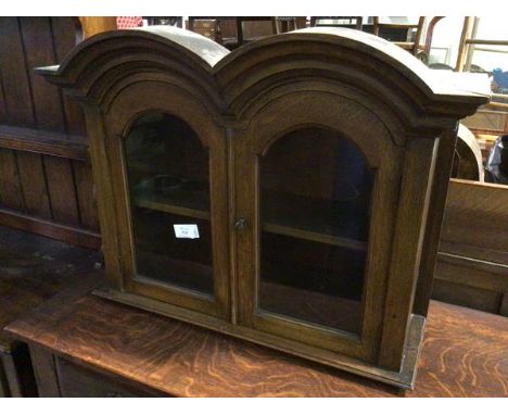 A 1920s/30s hanging cabinet, with a double arched pediment, above two glazed panel doors, with shelved interior (52cm x  69cm