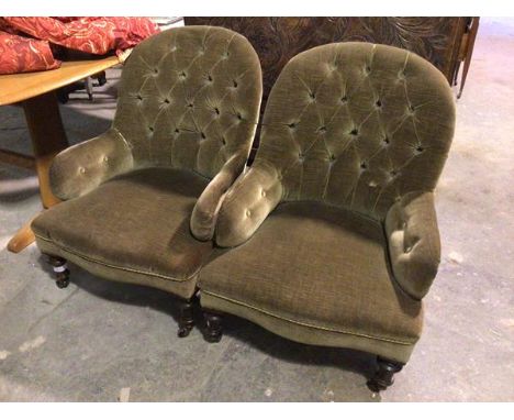 A pair of late Victorian library armchairs, with button backs and arms, in an olive green upholstery, on turned front support
