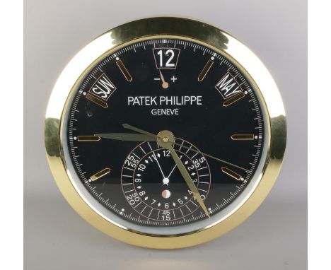 A Patek Philippe watch style wall clock, featuring a gold bezel and black dial, quartz movement, diameter 40cm.  Warping to d