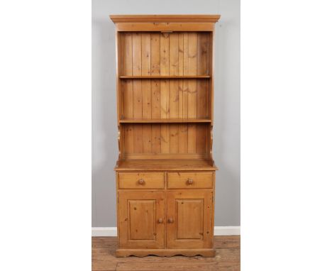 A slim pine dresser featuring two drawers over cupboard doors. Approx. dimensions 91cm x 44cm x 218cm.