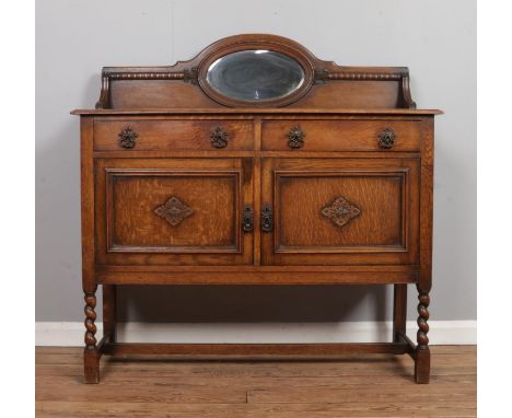 An oak mirror back sideboard, with carved panelled doors and egg and dart detailing. Raised on barley twist supports with cen