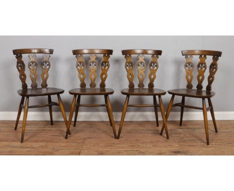A set of four Ercol dining chairs, with triple 'Fleur de Lys' splat. Bearing stickers to underside.