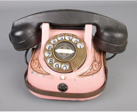 A vintage rotary Bell telephone in pink and black produced by the MFG company.