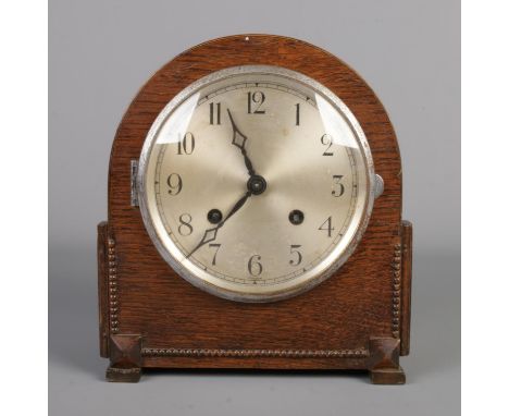 A vintage oak striking mantel clock with arched top, silvered dial and Arabic numerals, measuring W22 x D13 x H24cm.  Pendulu