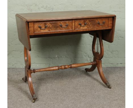 A mahogany two drawer sofa table. With lyre supports and lion paw feet.