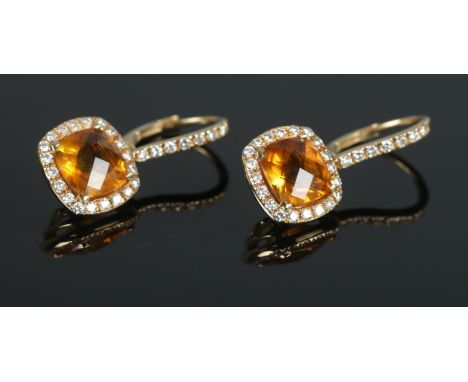 A pair of 18ct yellow gold mounted citrine and diamond earrings; the central citrine surrounded by a band of small diamonds, 