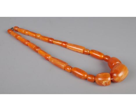 A large amber coloured necklace, possibly faturan, with large beads of various sizes. Length unclasped: 66g. Total weight: 14