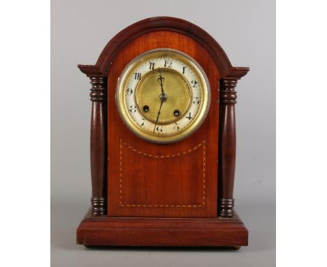 A British imported French mantel clock, mahogany case with rounded top supported by two columns, circular enamel chapter ring