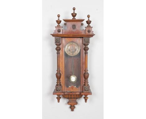 A Vienna style pendulum wall clock featuring turned supports and finials along with Roman numeral dial.