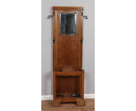 A slender oak hall stand, with coat hooks, mirror, storage box and stick stands. Height: 182cm, Width: 75cm, Depth: 29cm.  Bo