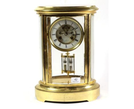 An oval shaped brass four glass mantel clock, circa 1890, bevelled glass panels, 4-1/2-inch enamel dial with Roman numerals, 