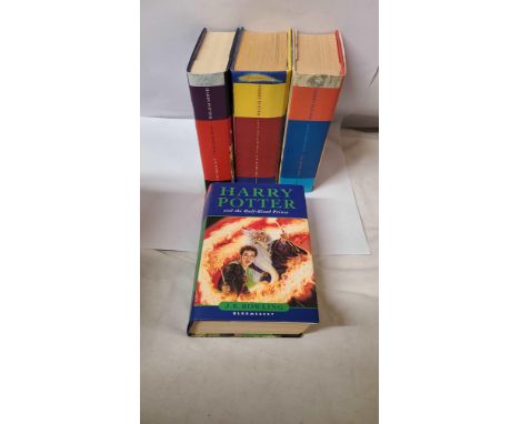A box containing four Harry Potter first edition hardback books by J.K. Rowling, all with printed dust jackets
