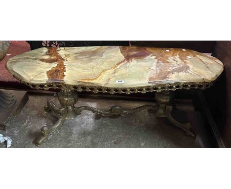 A 1.17m vintage shaped onyx topped coffee table, set on an ornate cast brass base with bulbous standard ends with swept feet