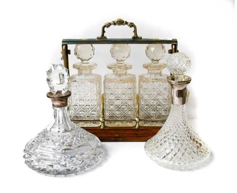 An early 20th century oak and silver plated three bottle tantalus with three decanters and stoppers, together with a cut glas