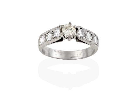 An 18 carat white gold diamond solitaire ring, the round brilliant cut diamond in a claw setting, to tapered shoulders inset 