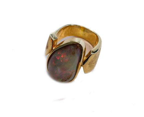 An opal ring, the pear shaped cabochon opal in a yellow rubbed over setting, to a textured shoulder plain polished shank, fin