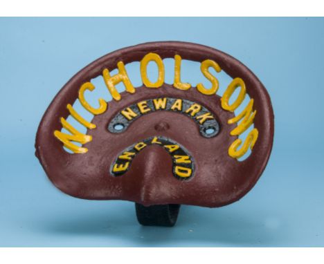 A vintage cast iron tractor seat by Nicholsons of Newark, painted maroon with yellow lettering, having attached cast iron sea