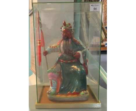 Probably Chinese seated ceramic figure of Guan Yu holding his halberd in glass case. Modern. (B.P. 21% + VAT)No obvious damag