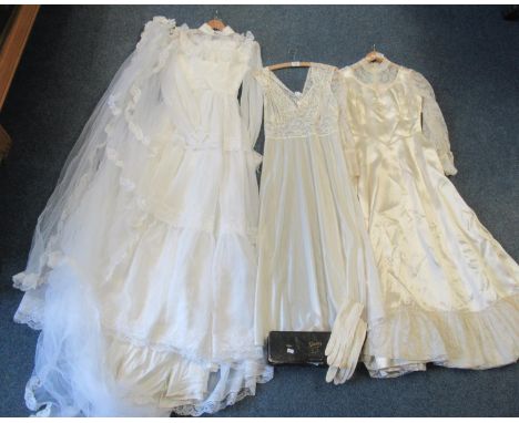 Two vintage 70's wedding dresses with lace detailing, high collars and long sleeves, one with a veil attached to a florally d