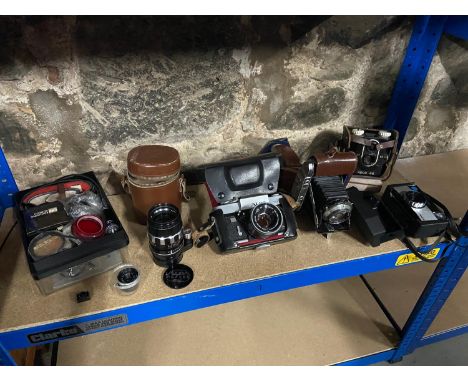 A Shelf containing a quantity of vintage cameras and equipement which includes Alpa Reflex 11e camera with lens, Schneider Al