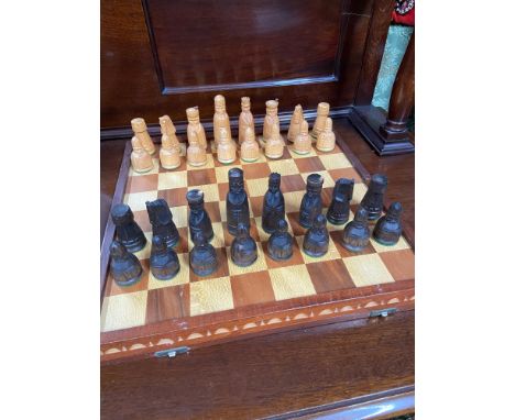 A Vintage wooden folding chess board with hand carved chess pieces. 