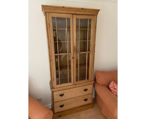 A Victorian stripped pine two door bookcase unit designed with two under drawers. Cabinet is made up of two Glass sectioned d