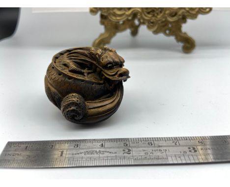 A Japanese netsuke of a curled up dragon, designed with black bead eyes. 
