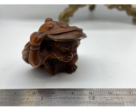 A Japanese netsuke of an Oni monster under a samurai helmet. Signed by the artist. 