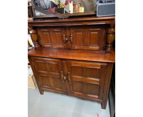 An Ercol style court cabinet. Designed with sliding locks and consists of four doors and fitted shelf interior to the base. 