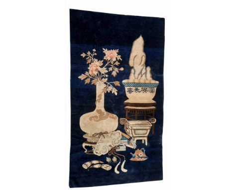 an antique, Chinese wall rug. Depicting items from the scholars' desk: a flower vase, a scholar rock, censer, books, jade pla