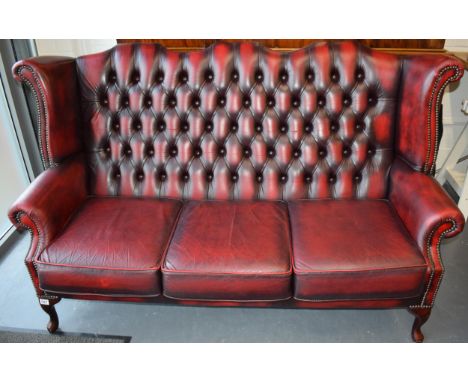 Queen Anne revival chesterfield wingback three seater sofa, with high back, in red leather with button back, raised on front 